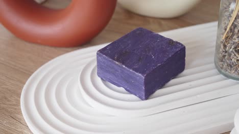 una barra de jabón de lavanda púrpura en un plato blanco
