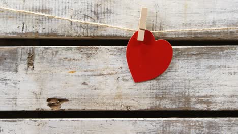 red heart paper cut pinned on the rope against wooden surface 4k