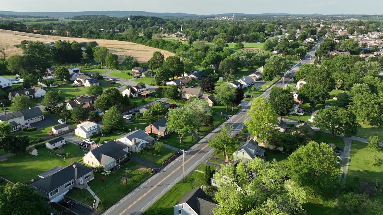 Atmosfera serena in un quartiere verde di una città americana. Tramonto dorato su una zona residenziale tranquilla e pittoresca. Case unifamiliari in una comunità idilliaca. Sorvolo aereo.