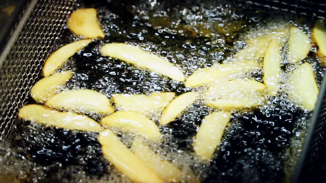 Cooking potatoes in boiling oil. French fries are deep fried at fast food restaurant