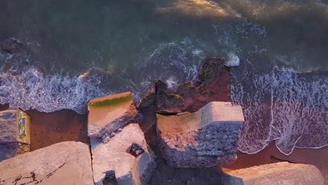 aerial birdseye view of abandoned seaside fortification buildings at karosta northern forts on the beach of baltic sea in liepaja, latvia, calm sea, golden hour, wide angle point of view drone shot