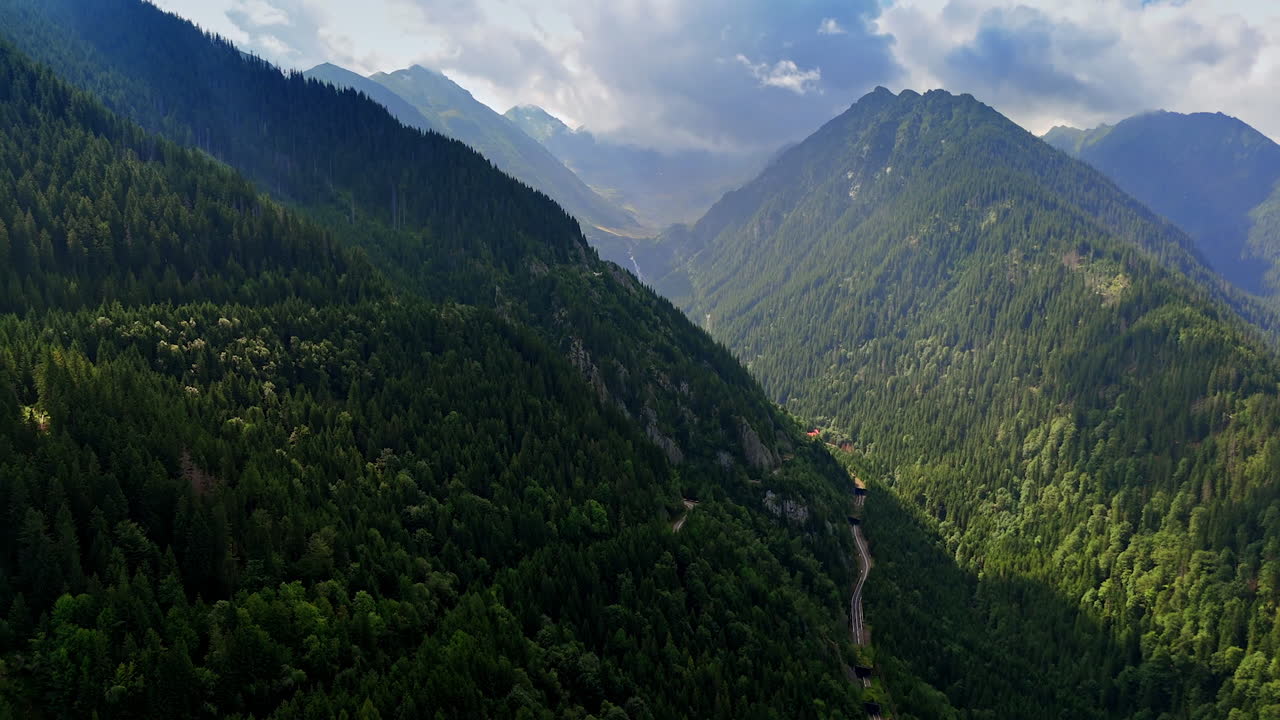 Vast green valley, mountain encircled. Lush green valley nestled between towering mountains under a dramatic cloudy sky during daylight hours