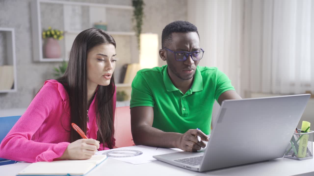 Portrait of freelance young man and woman. Young african man and caucasian woman working with laptop.