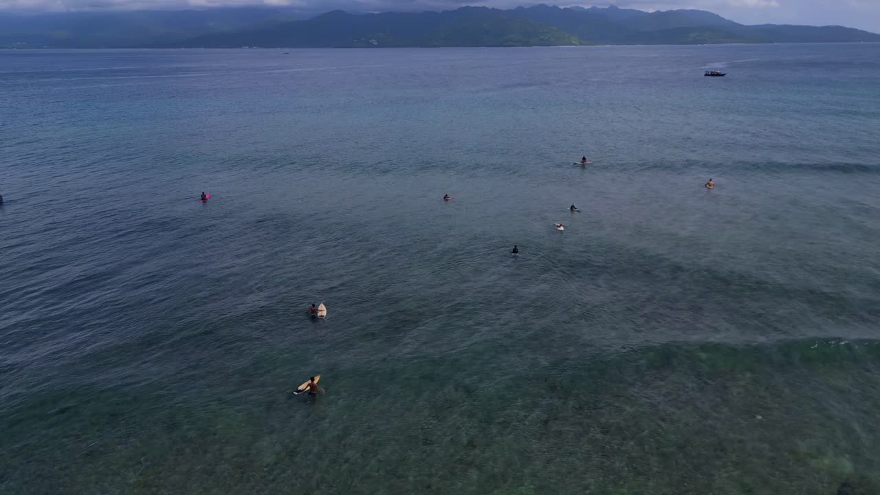 Lidé surfující a pádlování na paddleboardu na křišťálově čistých tyrkysových vodách útesu Gili ostrovů, užívající si tropickou dovolenou. Magický letecký pohled, široké orbitální panorama, přehled z dronu.