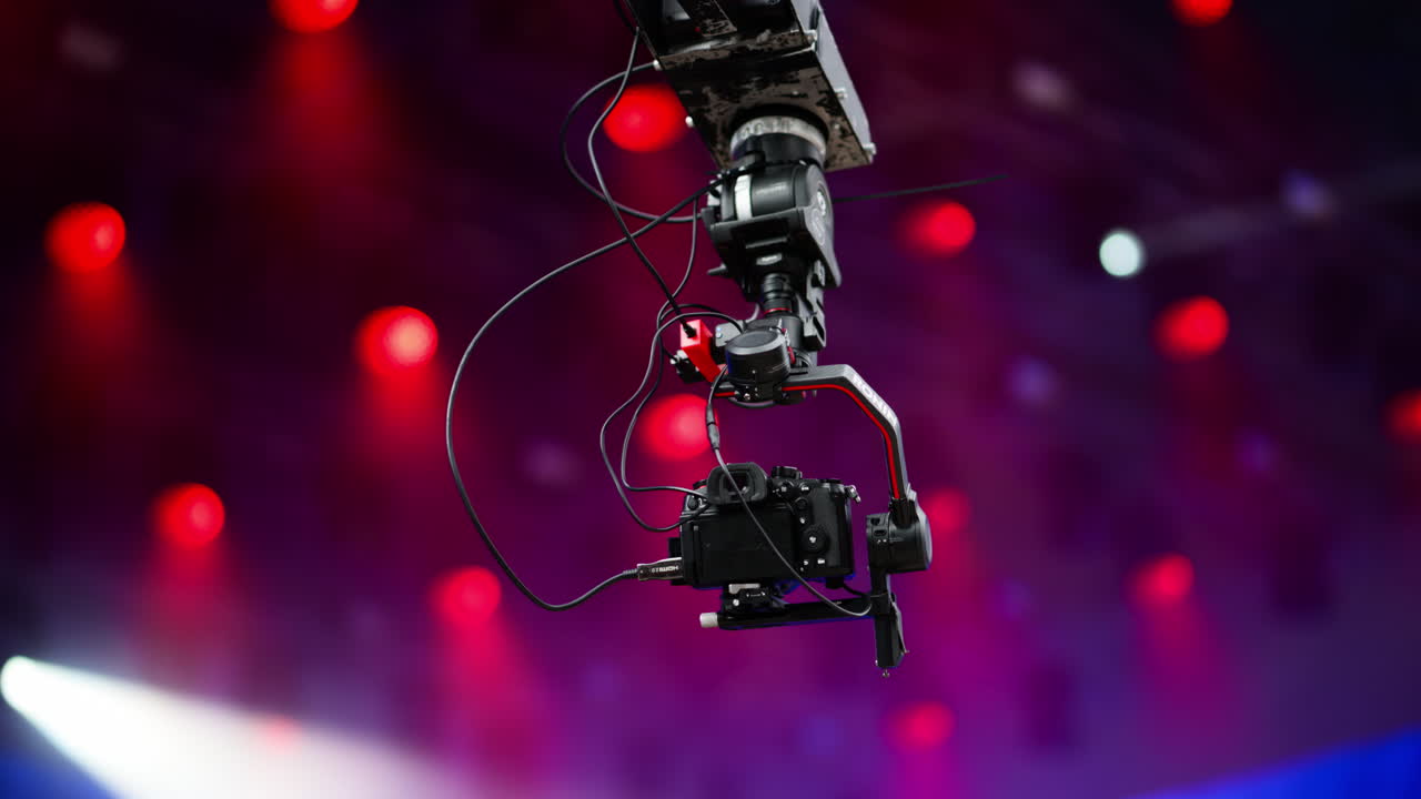 Camera crane captures an aerial view of a lively concert under bright colored and flashing lights