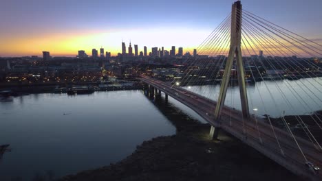 Puente-Y-Ciudad-De-Varsovia-Iluminados-Al-Atardecer-En-Vista-Aérea-Cinematográfica