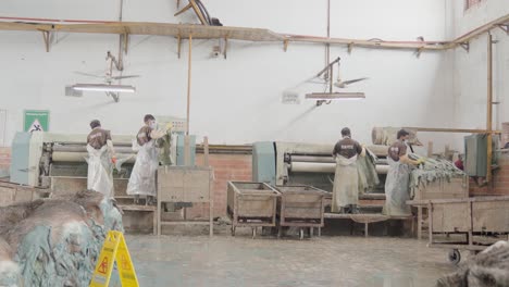 workers processing animal hides on the production line of a leather manufacturing factory in pakistan.