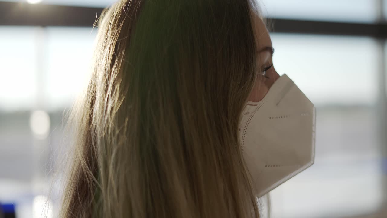 공항 에 서 있는 보호 마스크 를 입은 약간 혼란 스러운 여자