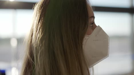 una mujer un poco confundida con máscara protectora de pie en el aeropuerto