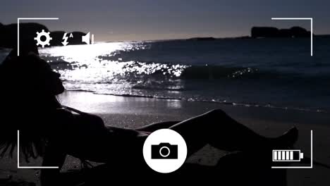 Digital-camera-interface-against-caucasian-woman-sunbathing-at-the-beach