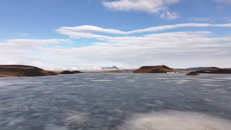 Frozen Lake Mývatn surrounded by volcanic craters and distant snowy peaks in Reykjahlíð, Iceland.