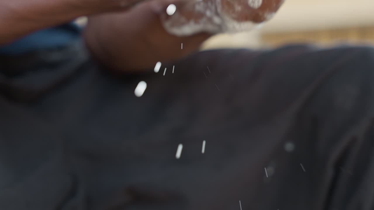 Black man washing clothes on lap, soapy hands and suds falling, black pants, gentle scrub, droplets and lather, porch light, domestic routine, tactile closeup of fingers and fabric