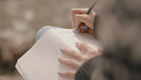 close up hands woman writing in diary journal teenage girl expressing lonely thoughts on seaside beach