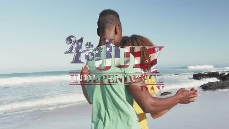 Animation-of-4th-of-july-independence-day-text-with-american-flag-pattern,-couple-dancing-on-beach