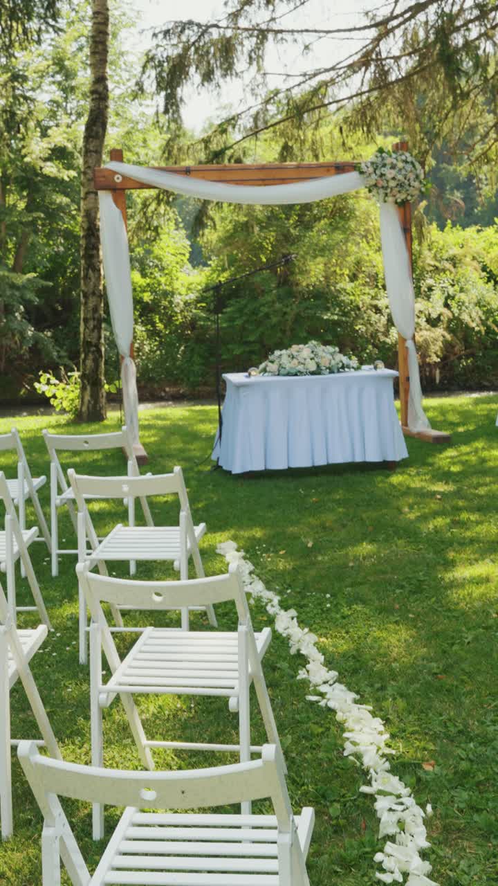 Path of white rose petals down the aisle of an outdoor civil wedding. Vertical