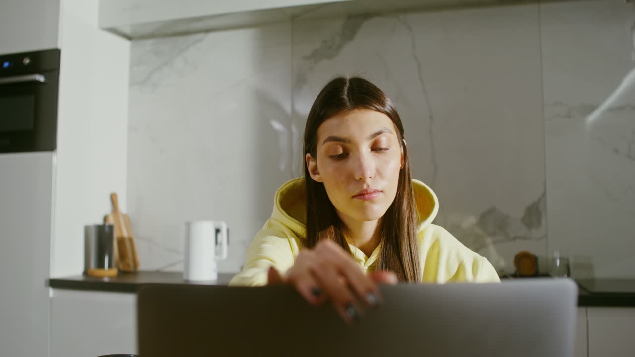 mujer joven trabajando en una computadora portátil en la cocina