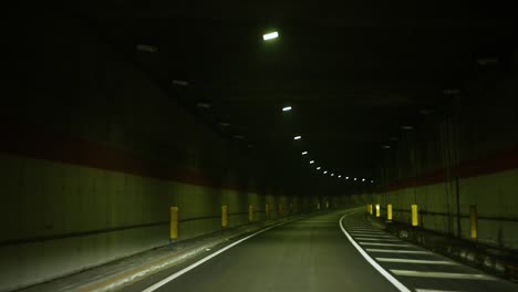 POV-of-a-car,-driving-slowly-through-a-dark-and-long-tunnel-at-night