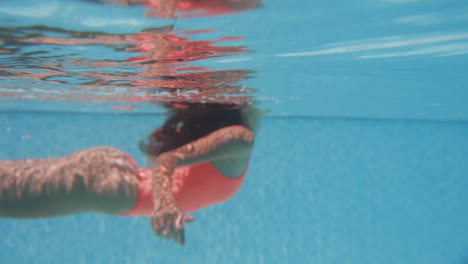 mujer nadando bajo el agua en una piscina