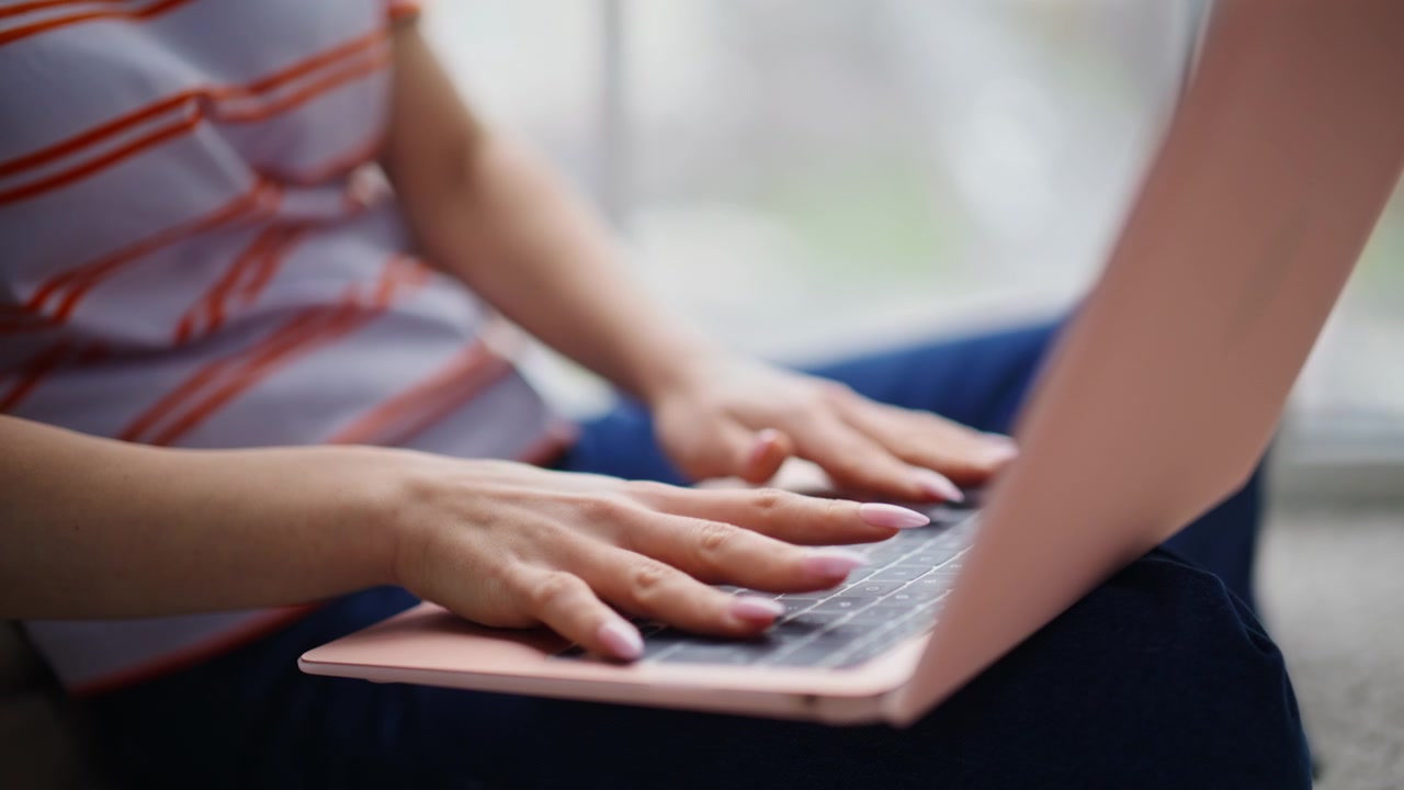 Velplejede hænder taster på computeren og laver online research hjemmefra. En freelancer arbejder.