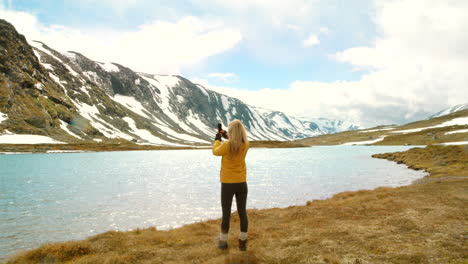 mujer tomando una foto de un pintoresco lago de montaña
