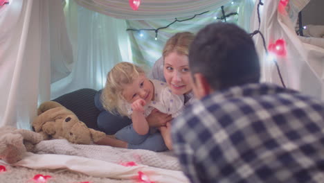 laughing parents with young daughter having fun in homemade camp in child's bedroom at home - shot on slow motion