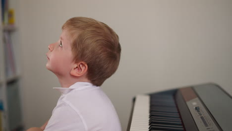 Dreaming-boy-sits-back-to-electric-piano-ignoring-lesson