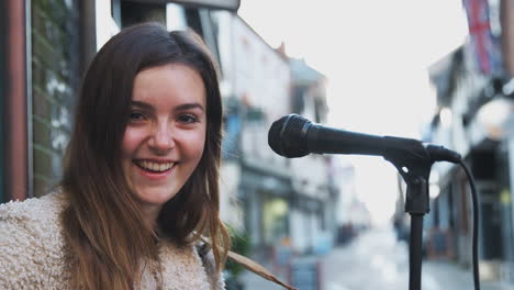 retrato de una músico femenina tocando la guitarra acústica al aire libre en la calle