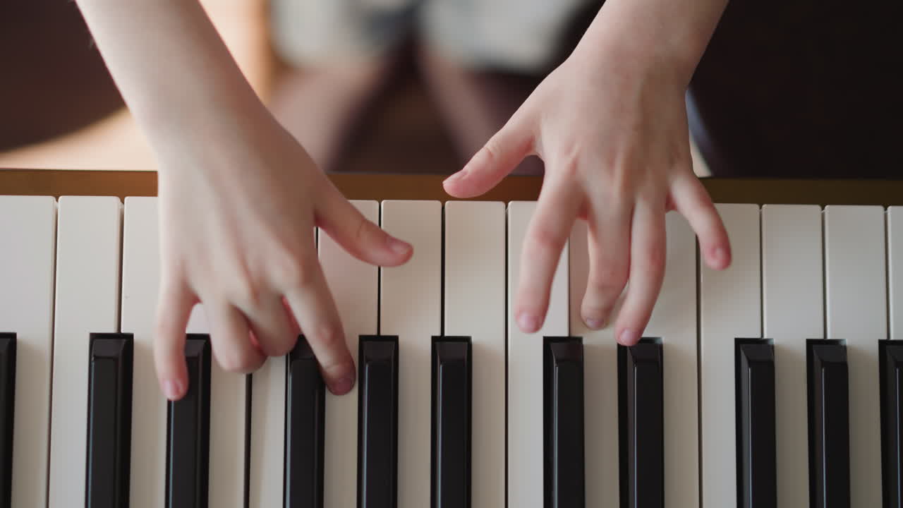 manos de niño tocando el piano eléctrico practicando la articulación de legato