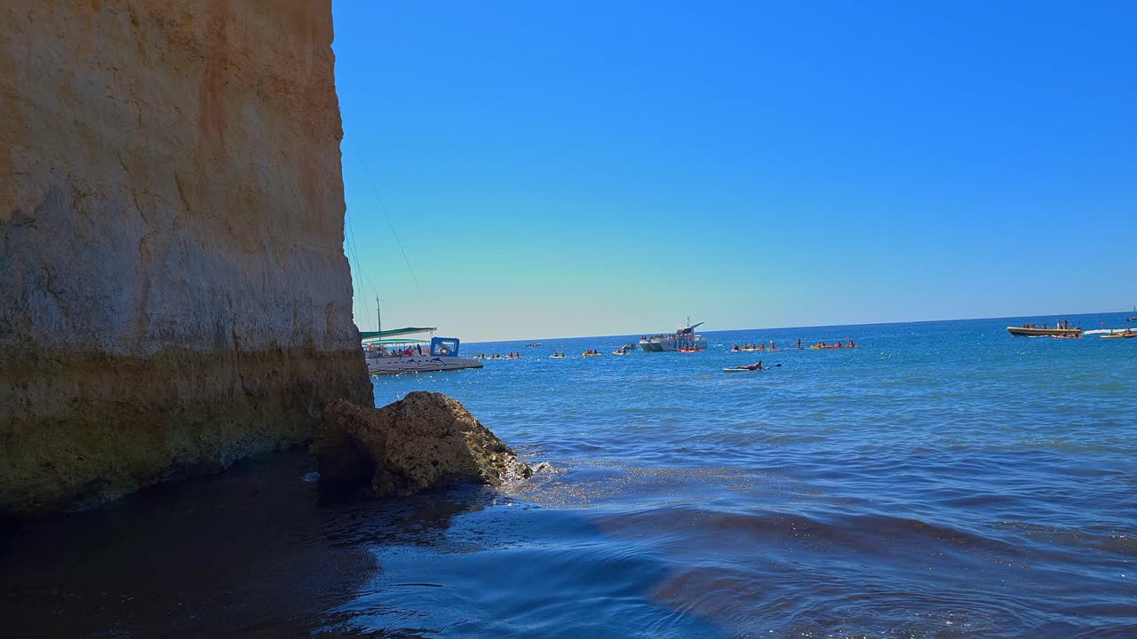 fotografía estática de barcos que navegan en el tranquilo mar azul de benagil, portugal