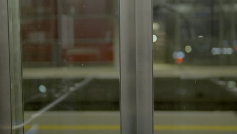 Puertas-De-Ascensor-De-Cristal-Que-Se-Abren-En-Una-Plataforma-Por-La-Noche-Con-Iluminación-Artificial