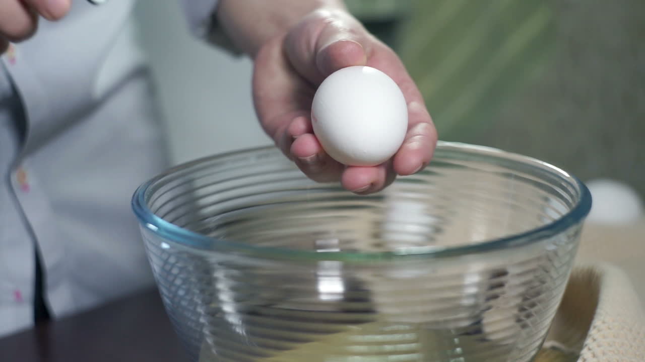Preparing food. Break egg. Baking ingredients. Eggs falling into glass bowl