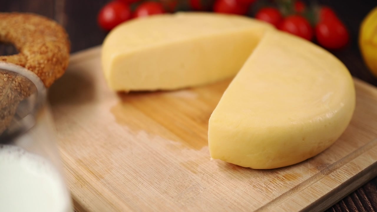 Formaggio fresco rotondo tagliato a metà su un tagliere di legno