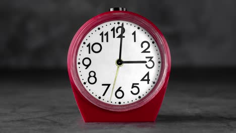 animación de bucle sin costuras con reloj de despertador de plástico rojo clásico con números grandes en un fondo borroso gris