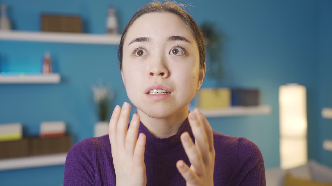 젊은 아시아 여성이 혼란스럽게 카메라를 쳐다보고 있습니다.