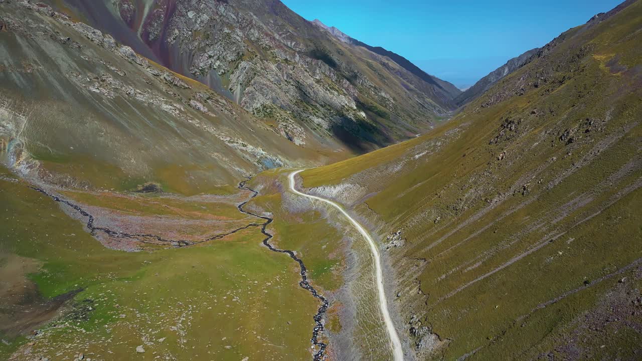 Aerial view of winding pass and stream cutting through valleys of Kyrgyzstan