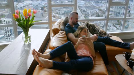 couple using digital tablet and mobile phone in living room 4k