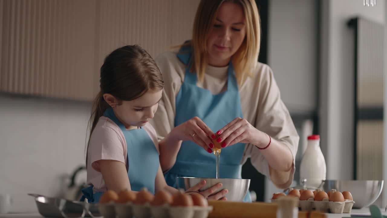 happy mom and daughter are cooking eggs in sunday morning woman is teaching her child to cook