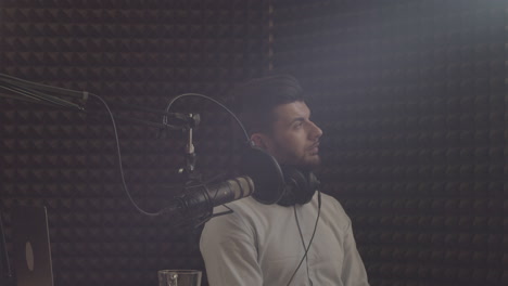 joven con barba enfocándose y teniendo un momento místico antes del programa en un estudio de grabación de radio