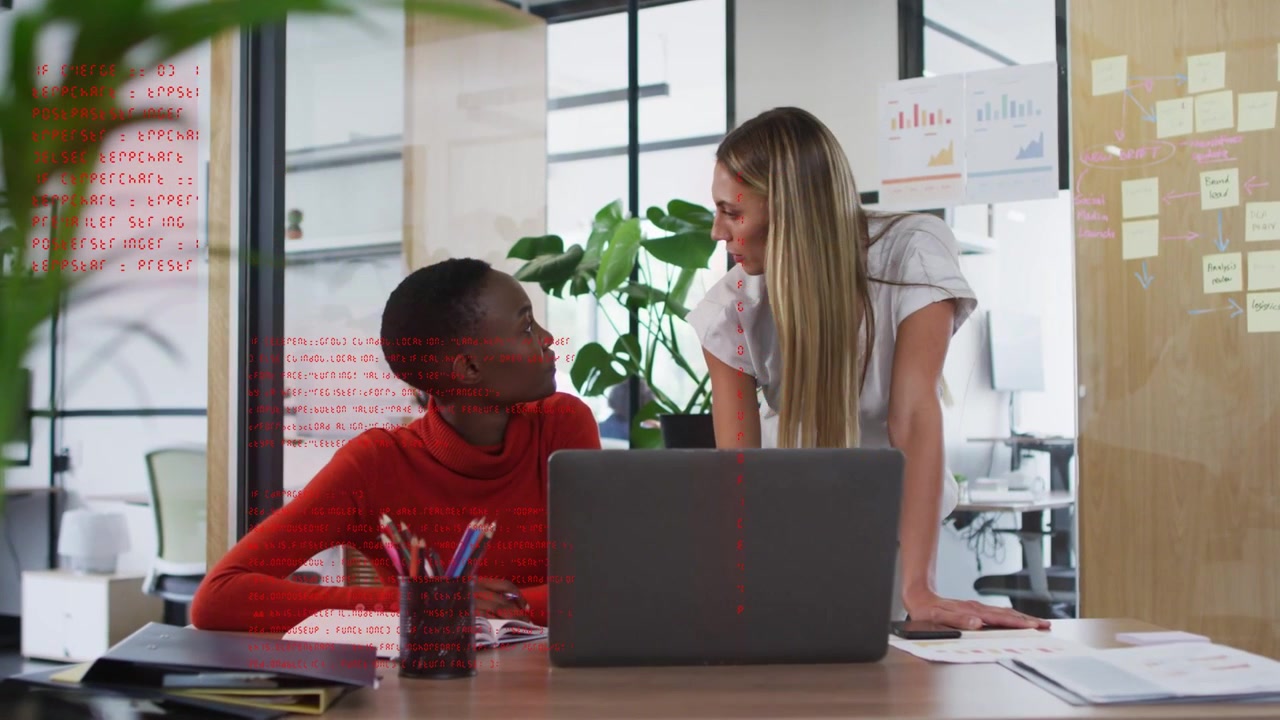 Woman pointing at laptop, peer leaning over desk reviewing, animated business charts appearing