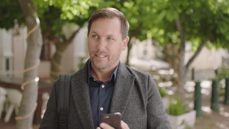 portrait of caucasian businessman texting browsing using smartphone mobile technology waiting in urban city street enjoying lifestyle