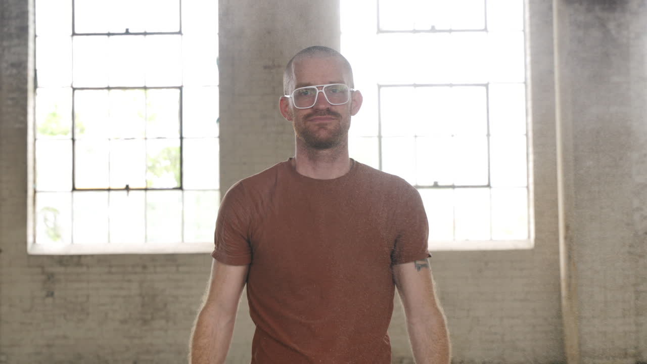 Man looking into camera and bringing his hands together to smack a powder and create an explosion.