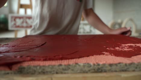 Primer-Plano-De-Un-Artesano-Profesional-Extendiendo-Tinte-Rojo-Con-Paleta