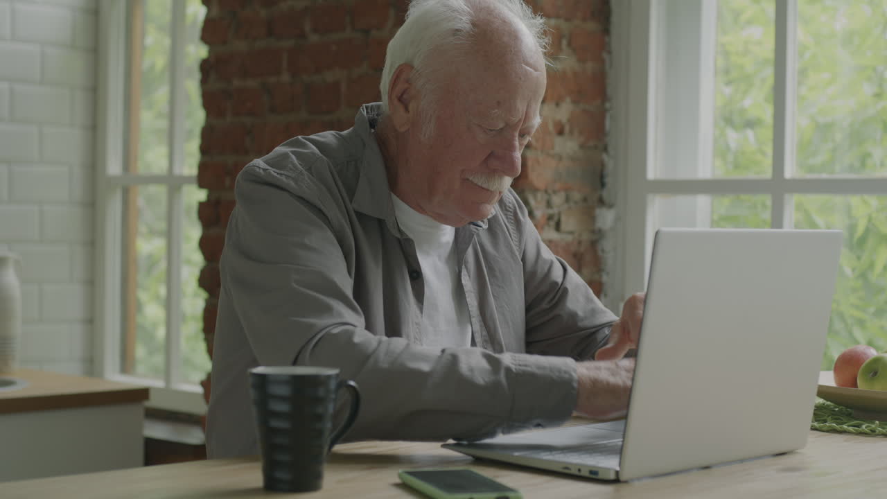 Senior Man Using Laptop in Kitchen