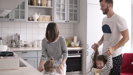 Una-Familia-Joven-Con-Dos-Niños-Baila-Y-Se-Divierte-En-La-Cocina.