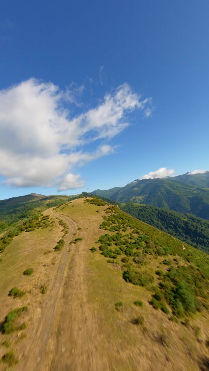 Prospettiva aerea FPV immersiva in prima persona della linea di cresta della vetta sulle colline di Coto Bello, con valli verdi e lussureggianti ad Aller, Asturie, Spagna