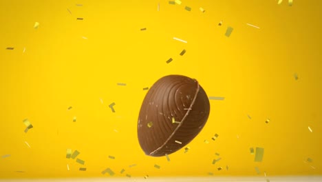 animation of chocolate easter egg falling and golden confetti flying on yellow background