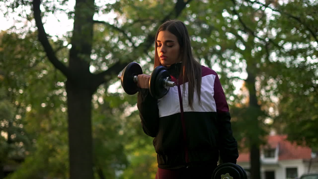 Woman working out in the park with dumbbells