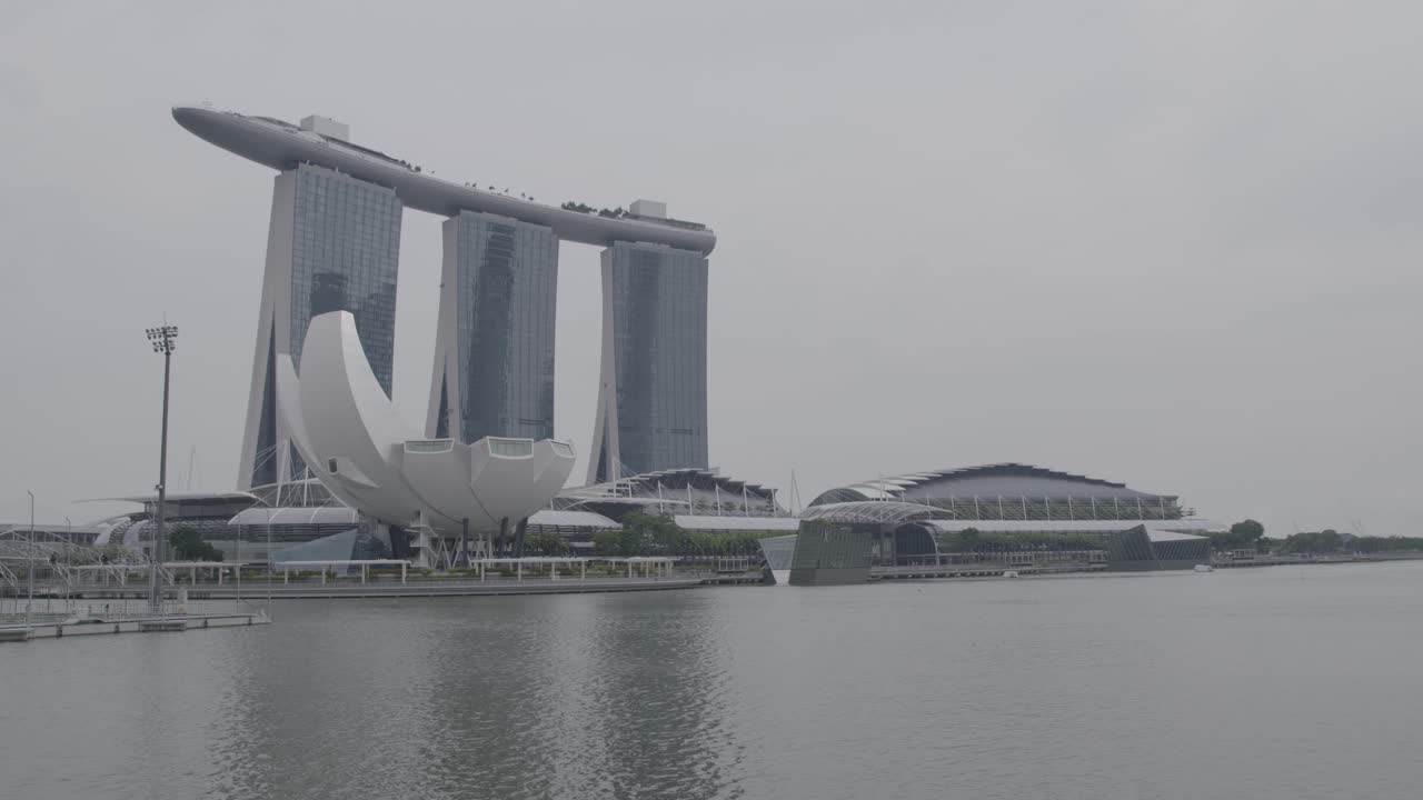 Wide shot: Static camera captures the impressive architecture of the Singapore skyline on a gray day