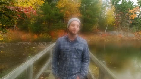 man walking on wood bridge in colorful fall leaves, dreamy handheld track wide