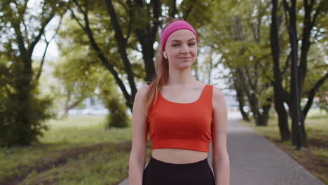 portrait of athletic sport runner girl training, listening favorite music song in earphones in park